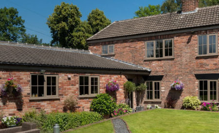 A brick house from the oustide on a sunny day with plenty of french casment windows.